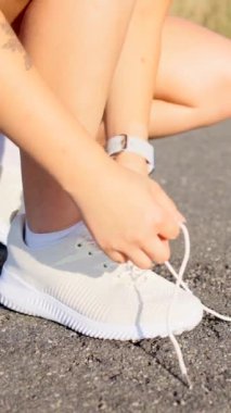 Yolda spor ayakkabı bağcığı bağlayan tanınmayan bir kadının yakınlaşması. Koşucu antrenmana hazırlanıyor..