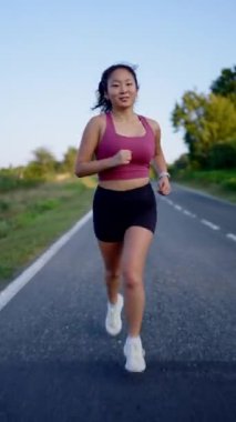 Koşan kadının tüm vücut uzunluğu. Asyalı 'nın açık havada antrenman yaptığı bir film..