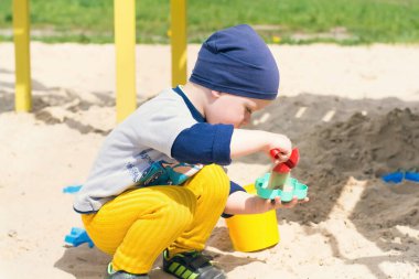 Küçük bir çocuk kumda oynuyor. Bir çocuk oyuncaklarla oynar