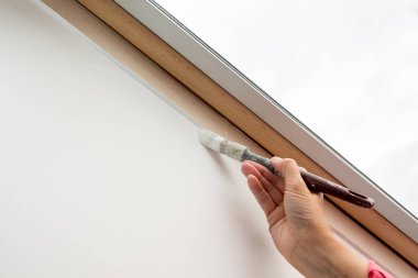 Brush painting the window recess of the sloping roof window - painting concept