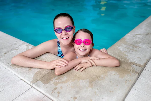 Happy sisters in swimming pool. Summer vacation and travel concept