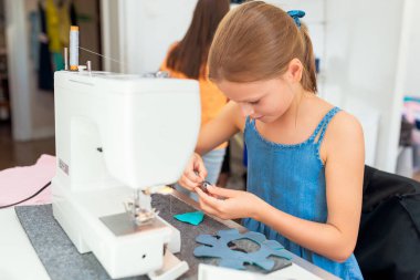 Bir kumaş parçasını dikmek için dikiş makinesi kullanan küçük bir kız.. 