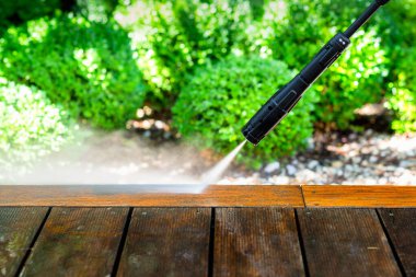 Terası elektrikli çamaşır makinesiyle temizliyor. Tahta teras yüzeyindeki yüksek su basıncı temizleyicisi.