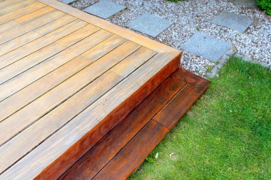 Close-up of a wooden deck - on the covered terrace - showing the process of restoration with a half-stained surface contrasting weathered and treated wood during a home improvement project  clipart