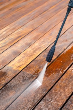 Terası elektrikli çamaşır makinesiyle temizliyor. Tahta teras yüzeyindeki yüksek su basıncı temizleyicisi.