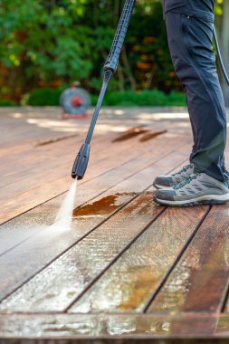 Terası elektrikli çamaşır makinesiyle temizliyor. Tahta teras yüzeyindeki yüksek su basıncı temizleyicisi.