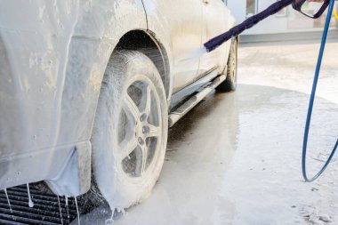 Bir SUV 'u yüksek basınçlı su ve köpükle yıkamak self-servis araba yıkama, güneşli bir günde aracın dışını temizlemek.