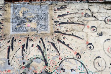 Çatlamış, yıpranmış duvar, soyulmuş boya ve kentsel bozulma deseni üzerine soyut grafiti ve dekoratif desen.