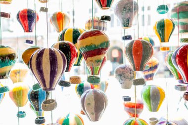 Renkli el yapımı seramik balon süslemeleri mağaza vitrininde asılı, parlak ışık, kaprisli ve sanatsal iç dekorasyonda sergilenen parlak çömlek süslemeleri