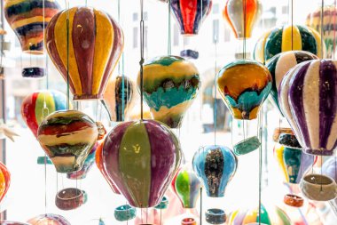 Renkli el yapımı seramik balon süslemeleri mağaza vitrininde asılı, parlak ışık, kaprisli ve sanatsal iç dekorasyonda sergilenen parlak çömlek süslemeleri