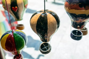 Renkli el yapımı seramik balon süslemeleri mağaza vitrininde asılı, parlak ışık, kaprisli ve sanatsal iç dekorasyonda sergilenen parlak çömlek süslemeleri