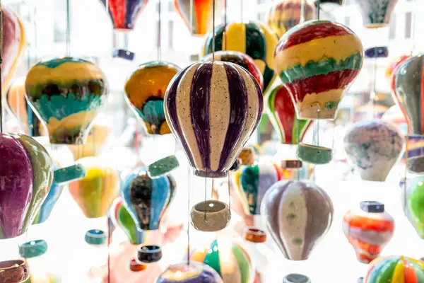 Renkli el yapımı seramik balon süslemeleri mağaza vitrininde asılı, parlak ışık, kaprisli ve sanatsal iç dekorasyonda sergilenen parlak çömlek süslemeleri