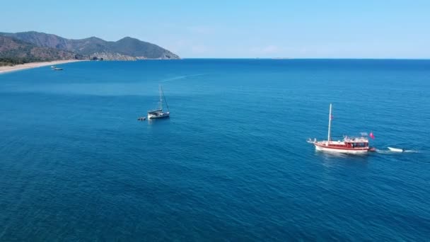 2隻のヨットが古代オリンパス近くの地中海で暖まります 写真はタカラ山脈と青い海と砂浜です — ストック動画