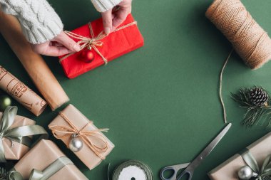 Yaratıcı hobi. Bir kadının elleri, el yapımı el yapımı Noel hediyesini sicim kurdelesiyle sarar. Noel hediyesi kutusunda fiyonk yapmak, zeytin masasında süslenmek, üst manzara..