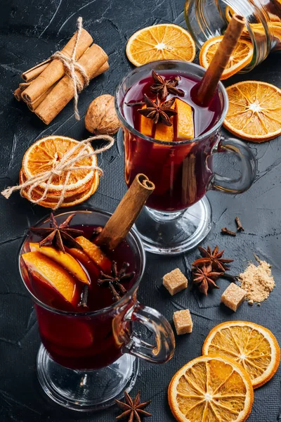Two cup of mulled wine on the table, near it are cinnamon, citrus fruits, dried oranges, star anise, cane sugar. Making mulled wine at home
