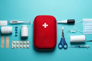 Home first aid kit on a blue background. The elements of the first aid kit are laid out on the table.