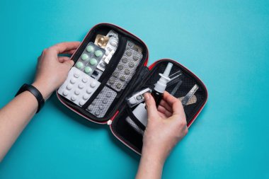 A woman opens a first aid kit. Home first aid kit on a blue background.