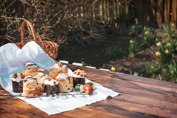 Easter baking on a wooden table in a spring garden. A lot of pastries on the table next to a basket for going to church.