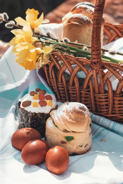 Easter baking on a wooden table in a spring garden. A lot of pastries on the table next to a basket for going to church.