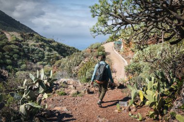 Bir turist kız Tenerife dağlarındaki Teno deniz fenerine doğru bir yürüyüş yolu boyunca yürür.