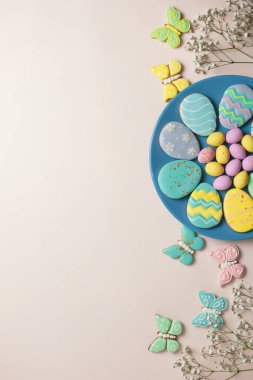 Pastel arka planda Paskalya afişi. Mavi tabakta ev yapımı zencefilli kurabiye, tavşan şeklinde Paskalya yumurtası ve kurabiye ve kelebek. Paskalya konsepti.