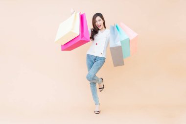 Güzel, gülümseyen, mutlu bir kadının portresi. Elinde çantalarla turuncu arka planda.