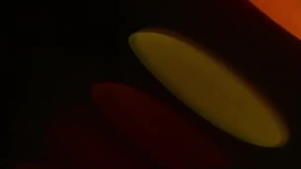 黒の背景に楕円形の斜めのボケでオレンジ色の光のフリッカーハイライト — ストック動画