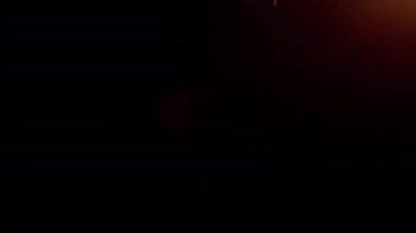 Gerçek ışık sızıntısı, ışık kırılması. Turuncu güneş ışınlarından gelen bokeh, çerçevenin üst tarafından sola doğru kayıyor. Siyah zemin üzerinde.