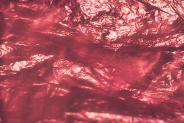 Yansıtıcı yüzeyleri olan buruşuk kırmızı folyonun yakın çekimi soyut desenler ve dokular yaratıyor. Resim ayrıntılı ayrıntıları ve materyalin parıldayan etkilerini vurguluyor, arkaplan veya sanatsal projeler için uygun.