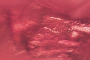 Yansıtıcı yüzeyi olan parlak, buruşuk kırmızı plastiğin yakın çekimi soyut doku oluşturur. Canlı renk ve ışık yansımaları dinamik, sanatsal titreşim verir.