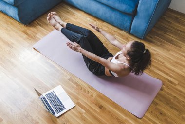 Kadın egzersiz minderinde oturuyor ve spor eğitimi yapıyor..