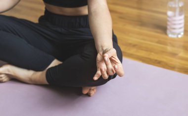 Shuni Mudra 'nın yojik el hareketiyle lotus pozisyonunda meditasyon yapan kadın..