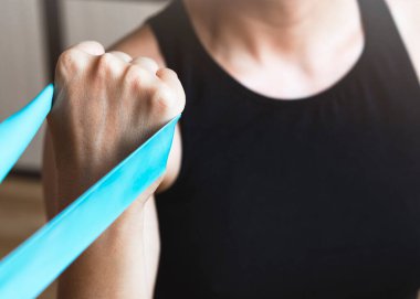 Kadın, direniş bandıyla pazılar için egzersiz yapıyor..