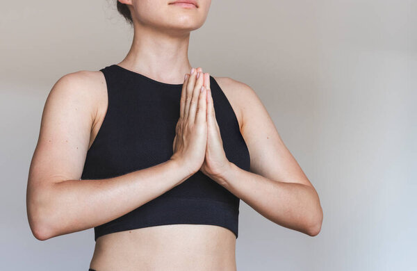 Женщина держит руки перед грудной клеткой, медитируя во время занятий йогой.