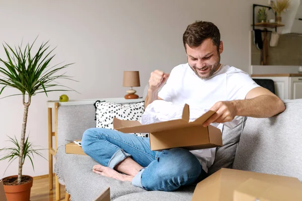 stock image Man rejoices at the received parcel with purchase from online store.