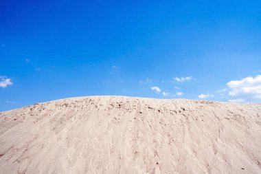 Mavi gökyüzüne karşı inşaat kumları tepesi.