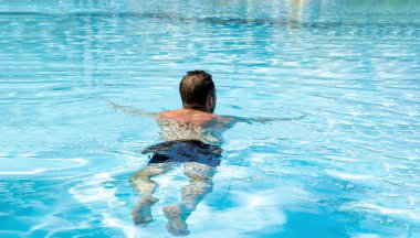 Dikiz aynasındaki adam yaz tatilinde havuzda dinleniyor..