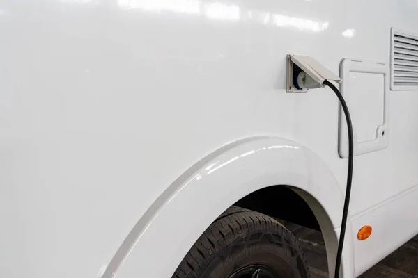 Charging white electric van close up. Electric vehicle charge cable.