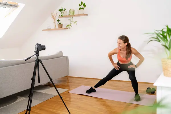 Athletic female online fitness coach vlogger recording video of sports exercise for her social media.
