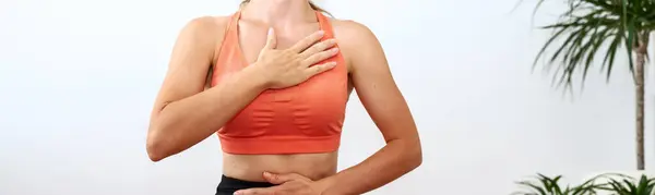 Female person doing yoga breathing exercise, hands on chest and belly. Wellness and meditation.