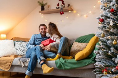 Noel hediyesi vermek. Bir kız erkek arkadaşına hediye verir ve onu yanağından öper..