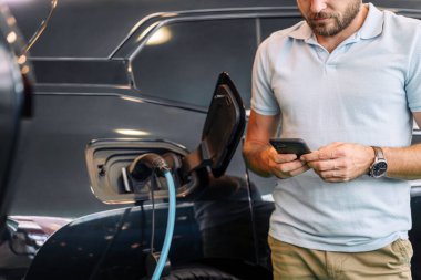 Elektrikli araba şarj istasyonu ve online cep telefonu ödemesi. Sürdürülebilir yaşam tarzı ve modern teknoloji.