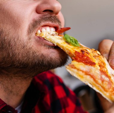 Erkek sakallı insan pizza yiyor. Yakın çekim fotoğrafçılık..