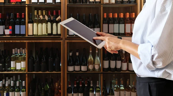 Wine shop manager using computer tablet while working at store.