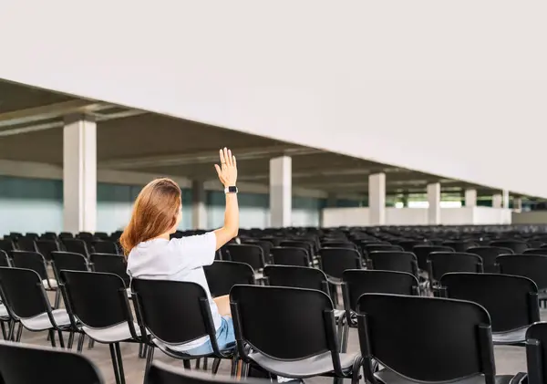 Bir kadın konferans sırasında soru sormak için elini kaldırdı. SSS konsepti. Halka açık oylamada el kaldırma. 