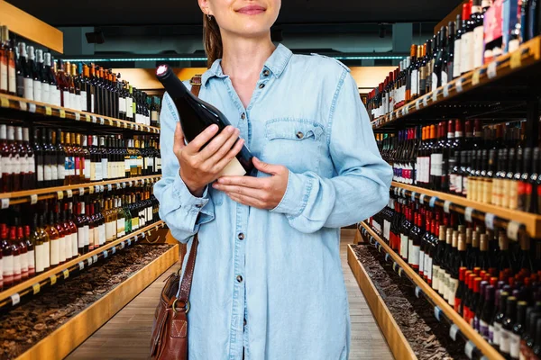 Woman consumer buying the wine in liquor store.