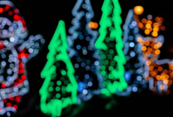 Bokeh parıldayan Noel sokak dekorasyonu. Noel ağacı şeklindeki bulanık çelenkler.