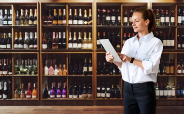 Businesswoman manager with digital tablet in hand standing in sales floor of liquor store. Business wine store.	