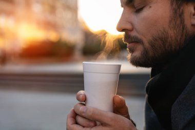 Kentte yürürken sıcak içkiden hoşlanan bir adamın yan görüntüsü. Sokak konseptine dönelim..