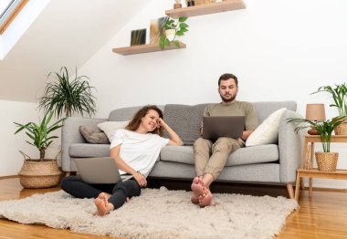 Evdeki genç çift dizüstü bilgisayarlarını otel araması ve rezervasyon için kullanıyor..